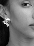 Close-up of a person wearing a sculptural silver earring.
