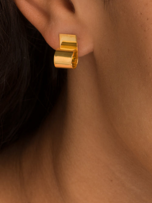 Gold earring worn by a person with dark hair.