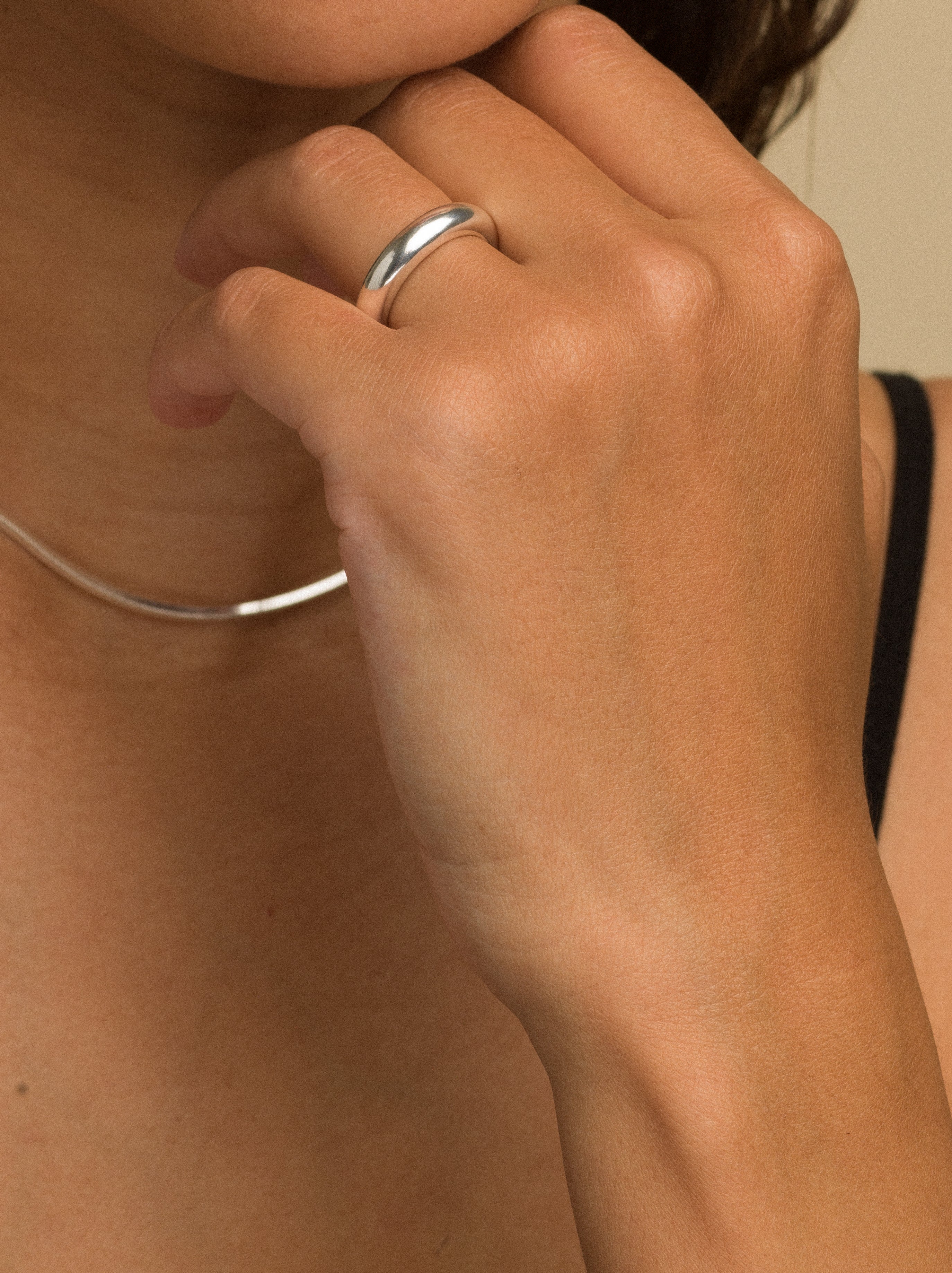 Close-up of a hand wearing a silver ring on a neutral background