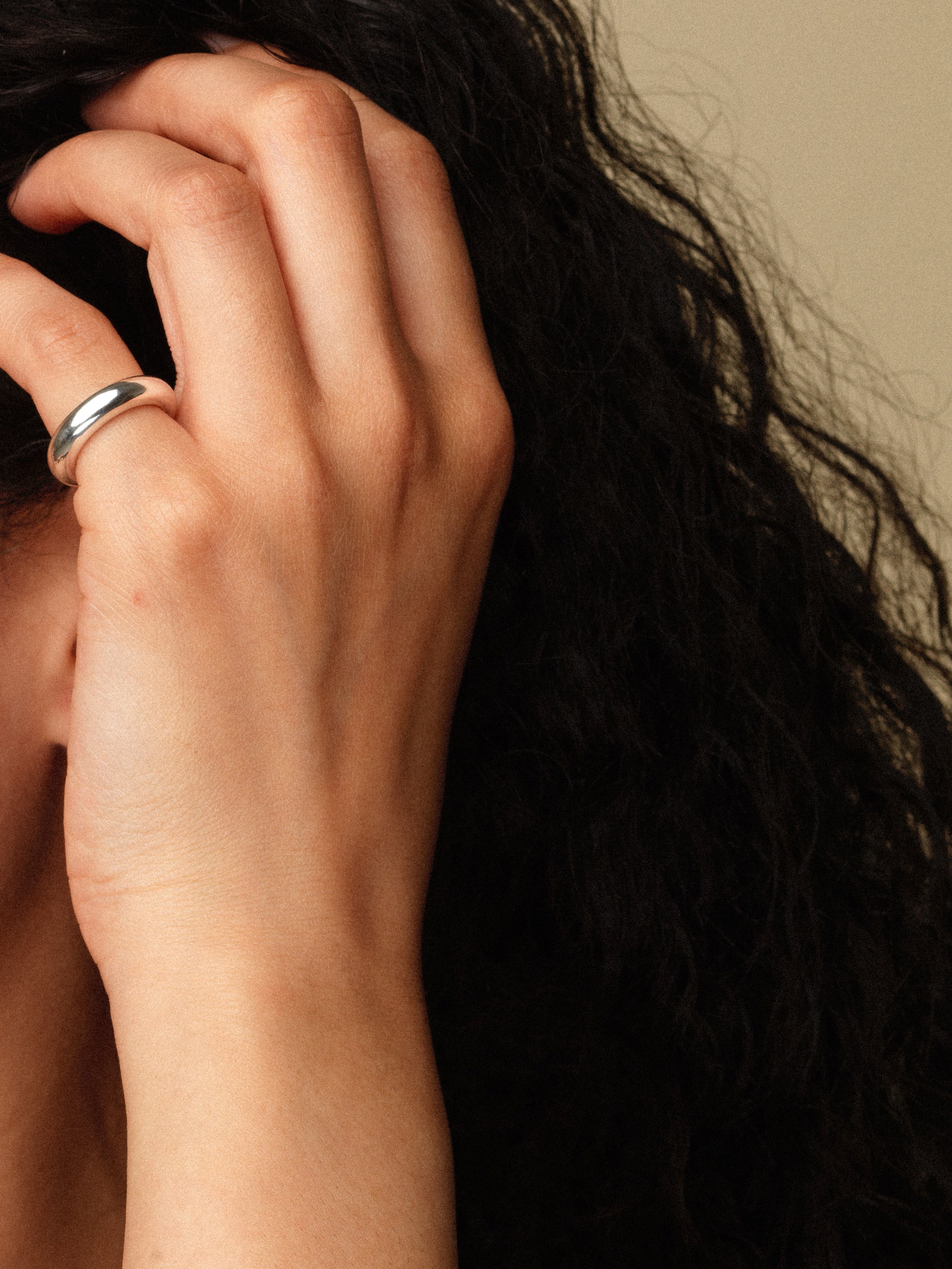 Hand with a silver pinky ring on a blurred background