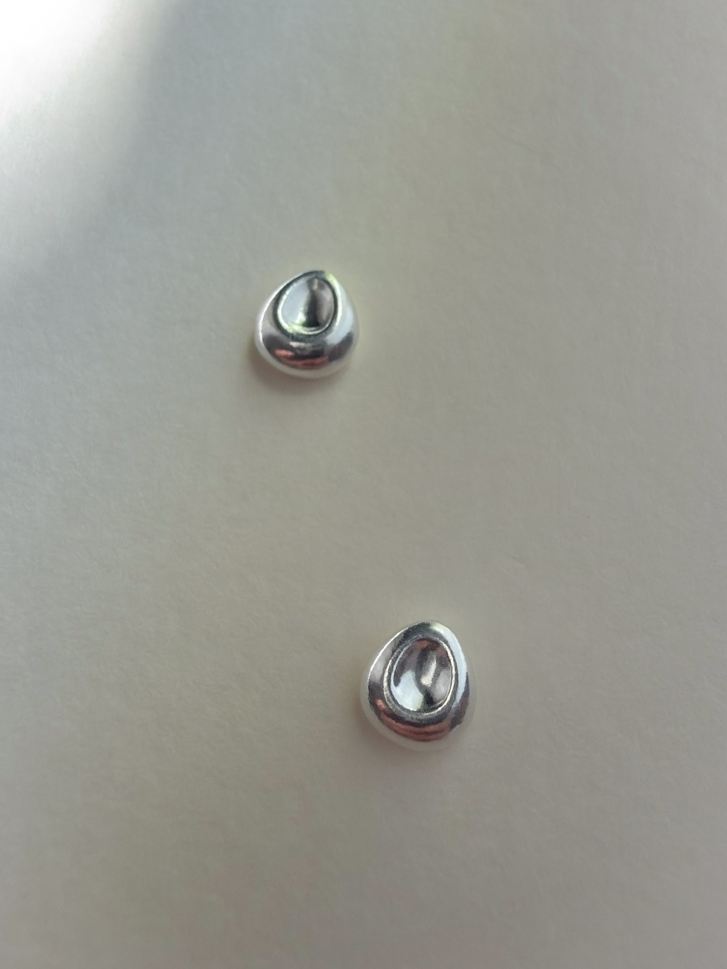 Close-up of Pebble Stud Earrings in recycled sterling silver showing the recessed centre.