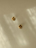 Pebble Stud Earrings in recycled gold vermeil resting on a softly textured surface with reflected light.